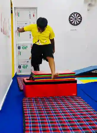 Boy clearing a padded obstacle during a kids gymnastics drill in Rajeev Nagar, Patna