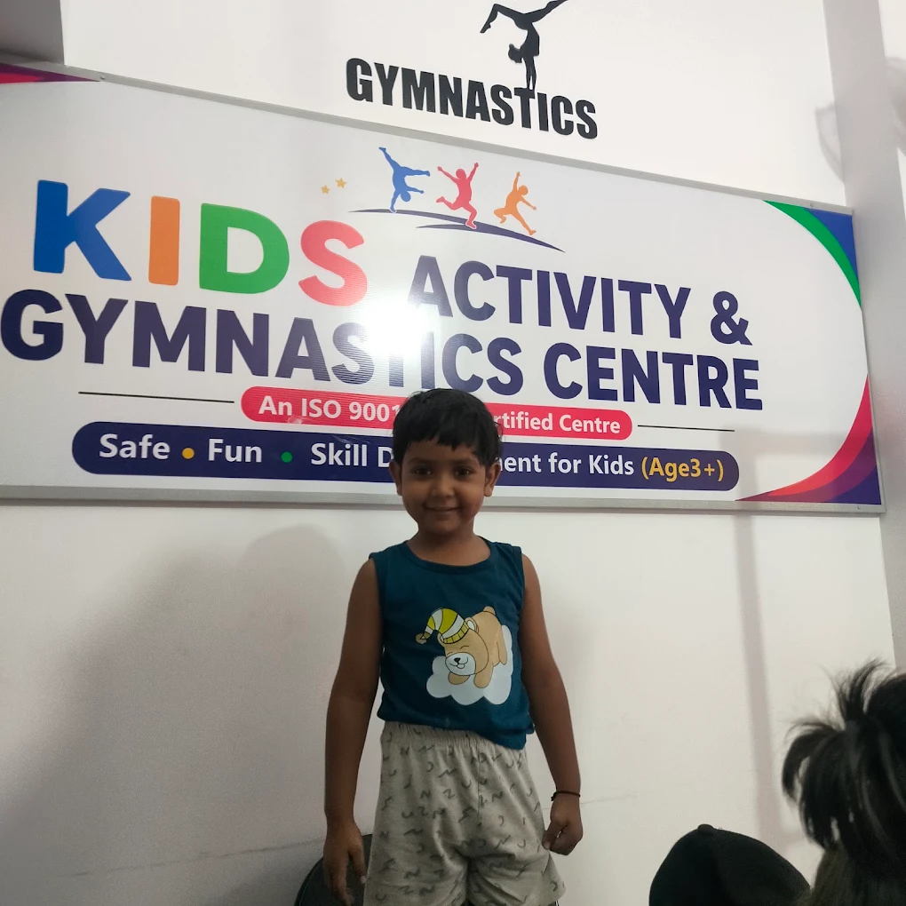 A boy standing below the Kids Activity & Gymnastics Centre sign
