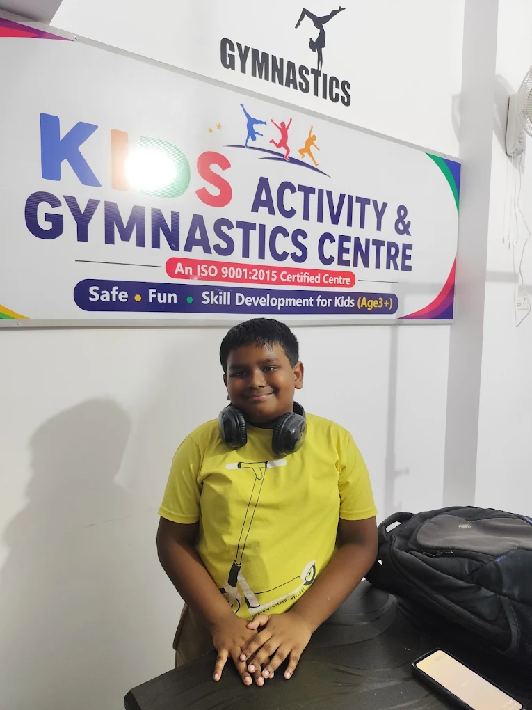 A boy smiling below the Kids Activity & Gymnastics Centre sign