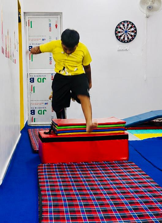 A boy jumping across padded platforms during a gymnastics obstacle activity