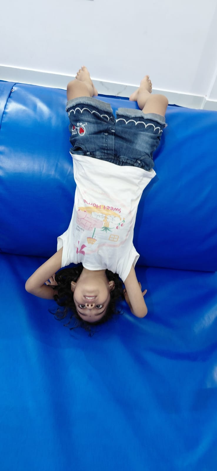 A child practicing an inverted gymnastics pose on a blue padded mat