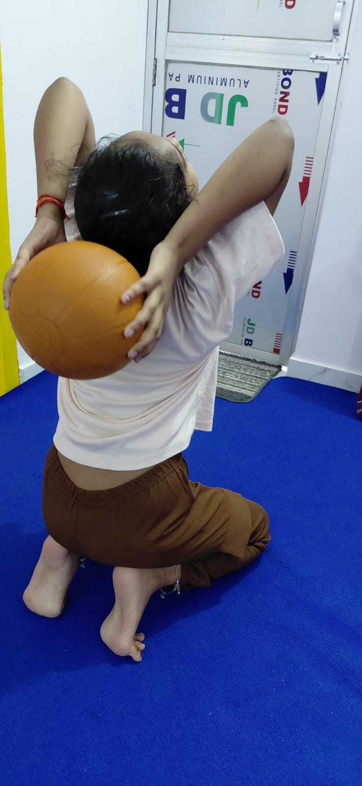 A child stretching backward with a gym ball during a coached class