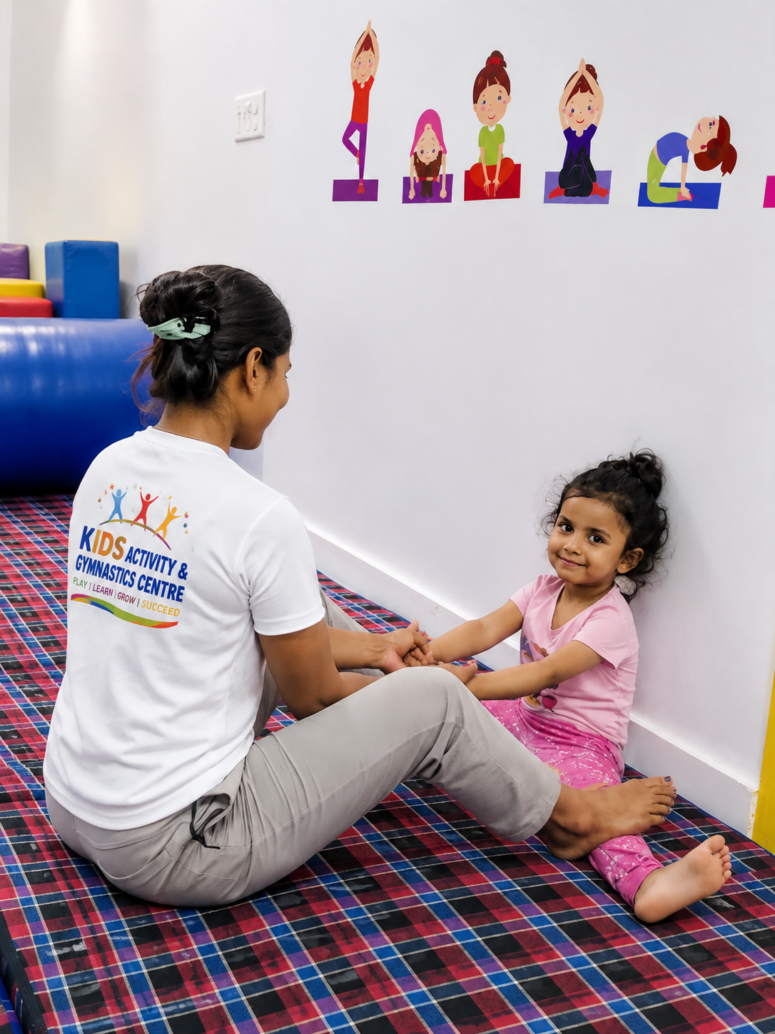 A coach guiding a child through a seated stretch at Kids Activity & Gymnastics Centre